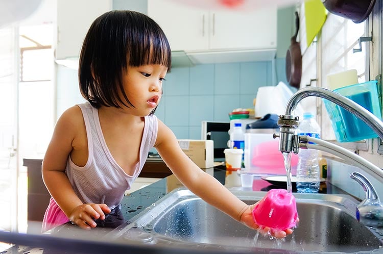 Child leaning over sink