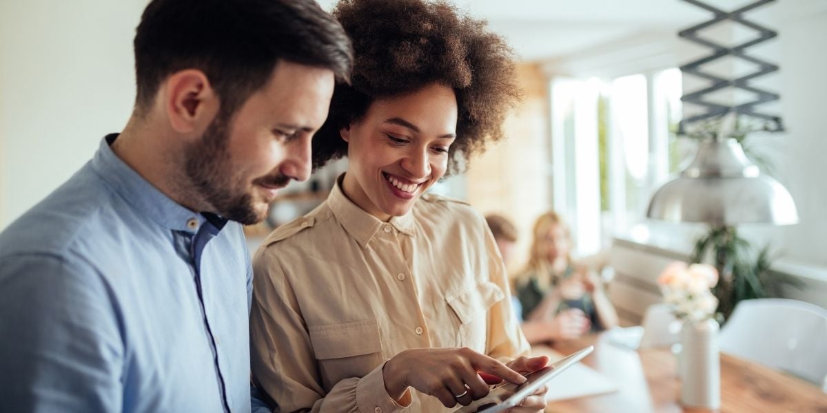 Two realtors smiling at the real estate content they've created to attract clients