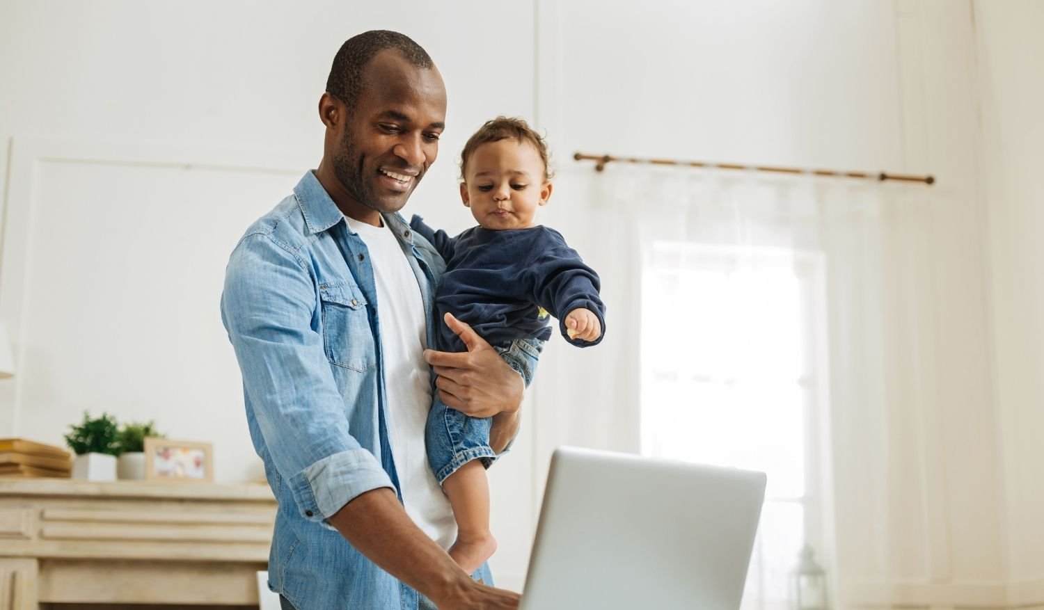 A father holding his son while evaluating the pros and cons of buying a house during a recession